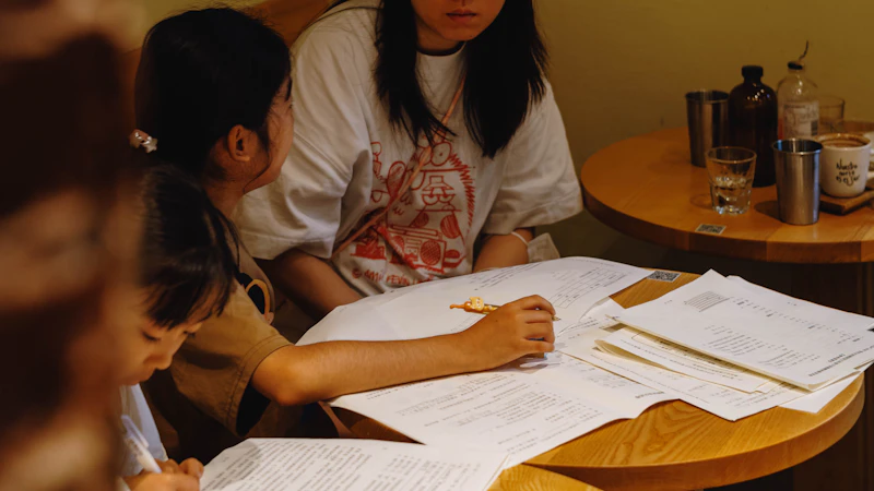 Een moeder en dochter bekijken samen papieren documenten aan een tafel