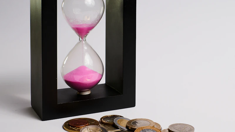 Een zandloper met roze zand naast een stapel euromunten, symbool voor sparen doorheen de tijd