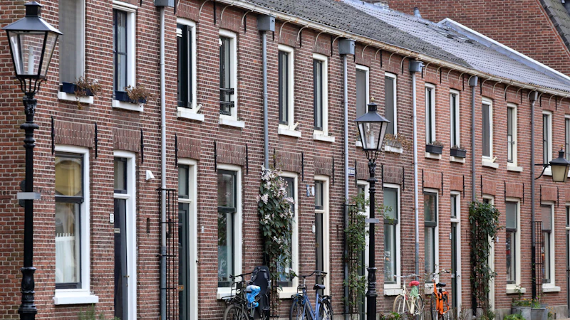 Een rij bakstenen rijwoningen met fietsen ervoor in een Vlaamse straat