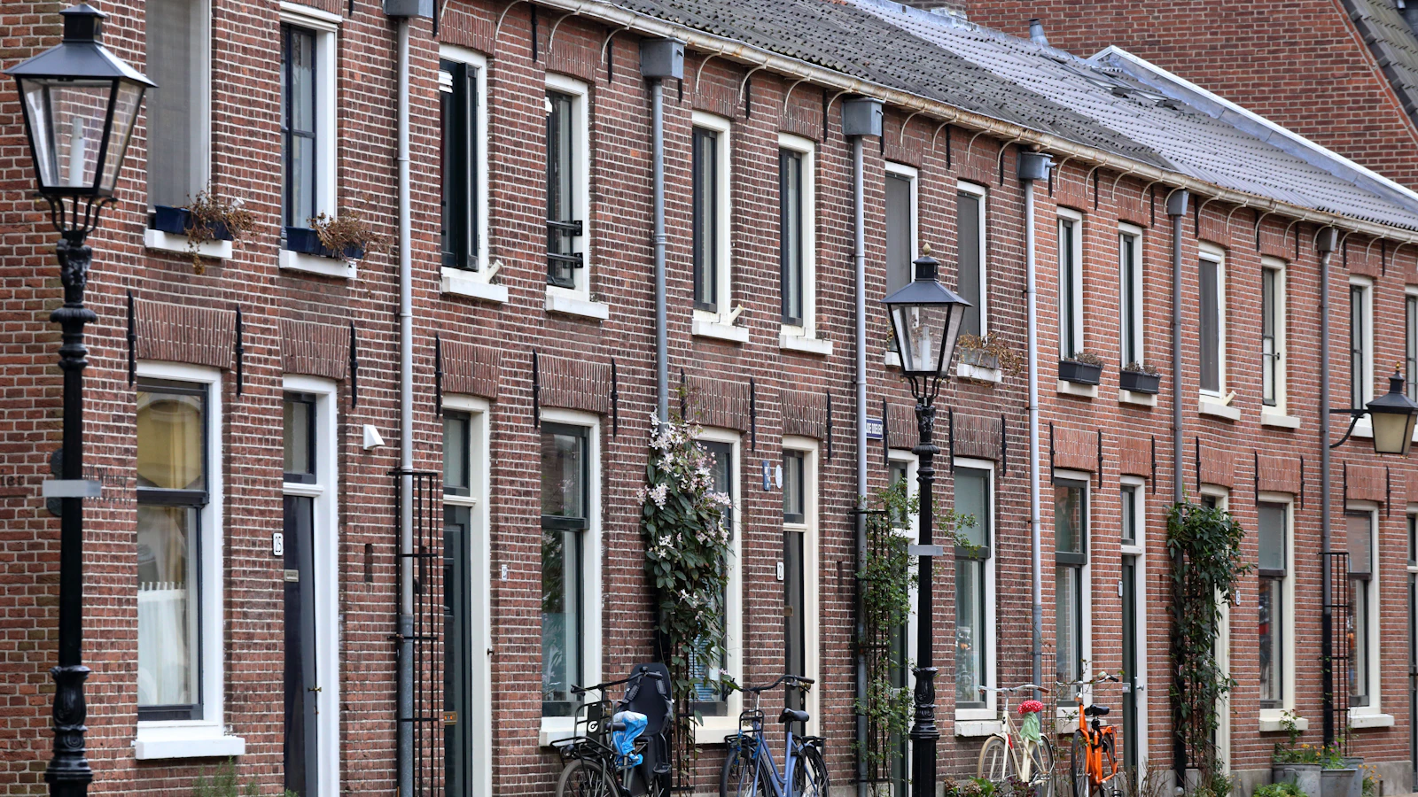 Een rij bakstenen rijwoningen met fietsen ervoor in een Vlaamse straat